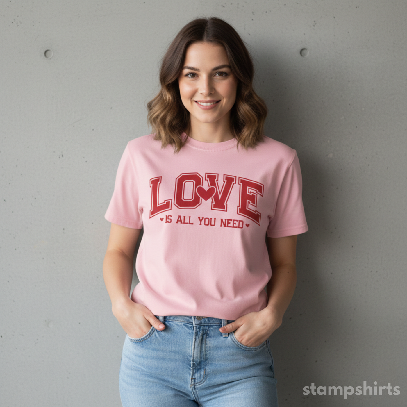 Woman wearing a pink t-shirt with 'LOVE is all you need' text against a gray wall. image 3