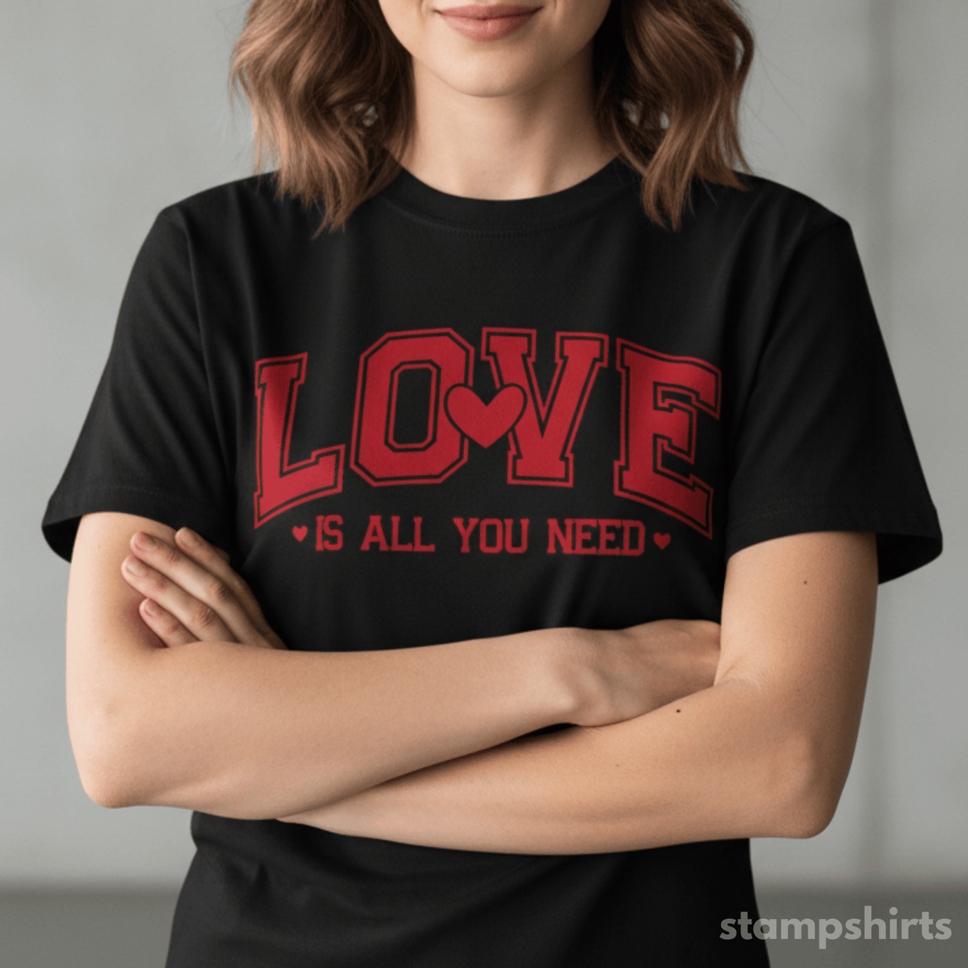 Person wearing a black t-shirt with red text 'LOVE IS ALL YOU NEED' on a plain background image 1