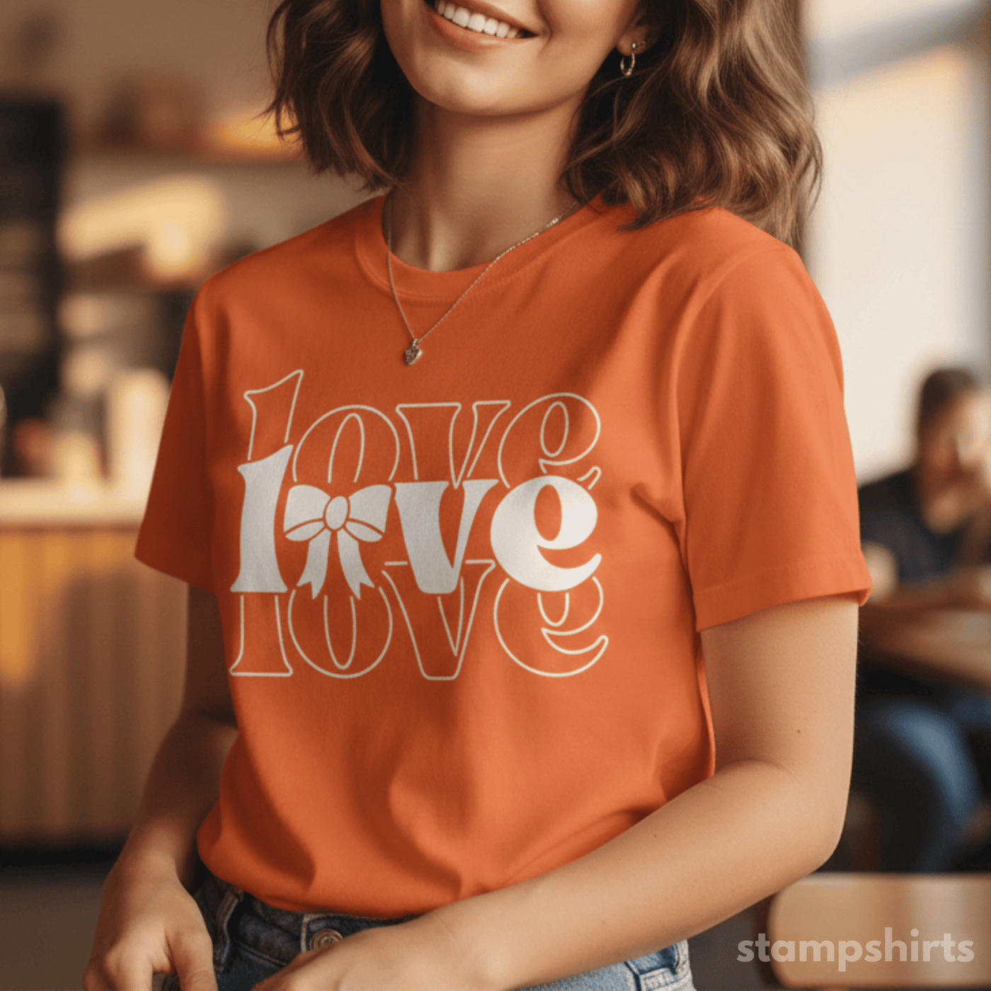 Person wearing an orange t-shirt with 'LOVE' design, sitting indoors. image 1