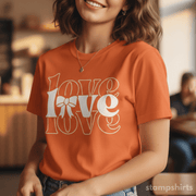 Person wearing an orange t-shirt with 'LOVE' design, sitting indoors.