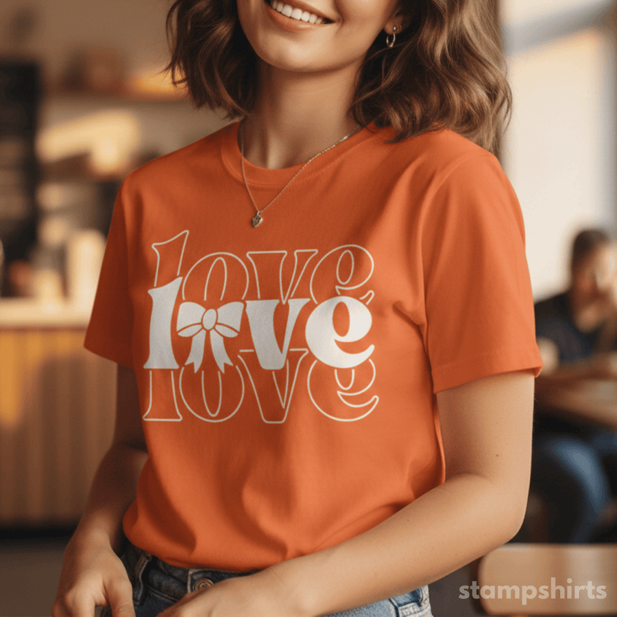 Person wearing an orange t-shirt with 'LOVE' design, sitting indoors.