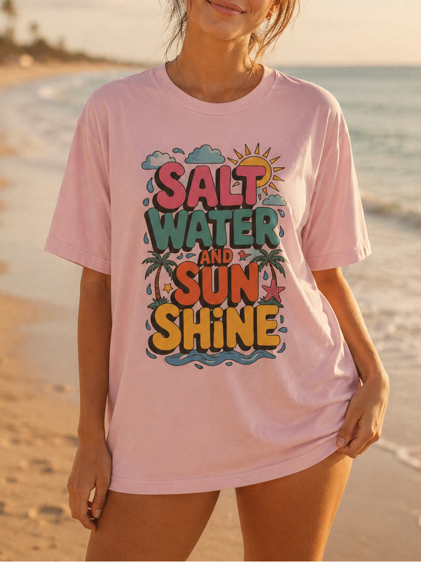 Woman wearing a pink t-shirt with 'Salt Water and Sunshine' text on a beach.