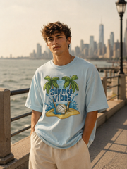 Person wearing a 'Summer Vibes' t-shirt with palm trees and a beach scene, standing by a waterfront with a city skyline in the background.