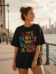 Woman wearing a black t-shirt with colorful text by a waterfront with city skyline.