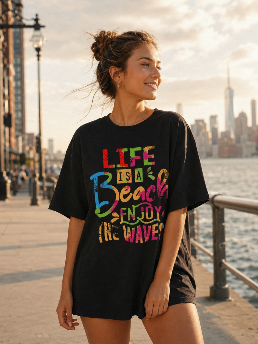 Woman wearing a black t-shirt with colorful text by a waterfront with city skyline.