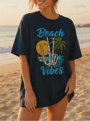 Woman wearing a 'Beach Vibes' t-shirt on a beach at sunset