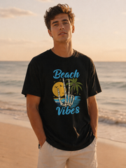 Man wearing a black t-shirt with 'Beach Vibes' design on a beach at sunset.