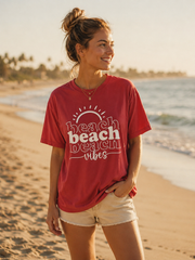 Woman wearing a red 'beach vibes' shirt on a beach