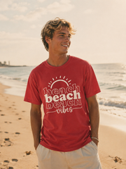 Man wearing a red 'beach vibes' t-shirt on a beach