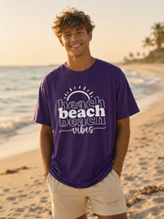 Man wearing a purple 'beach vibes' t-shirt on a beach