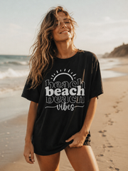 Woman wearing a black t-shirt with 'beach vibes' text on a beach