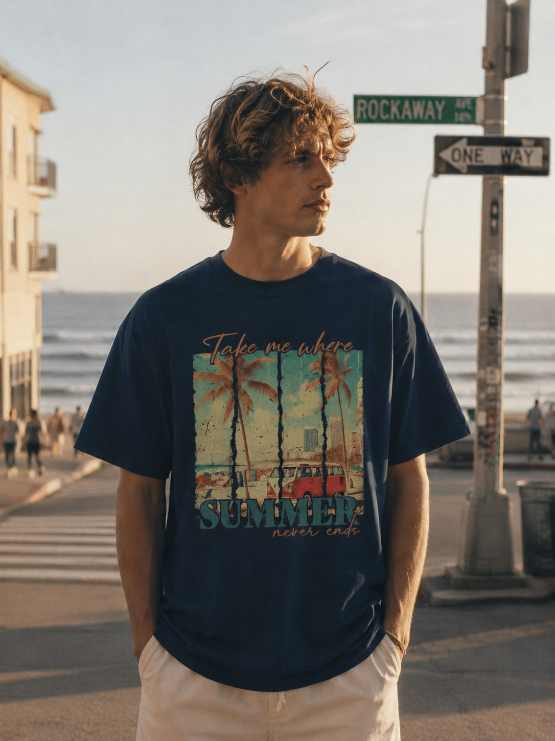 Man wearing a navy blue t-shirt with a beach graphic and 'Summer' text, standing on a street near the ocean.