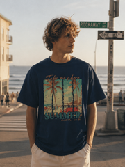 Man wearing a navy blue t-shirt with a beach graphic and 'Summer' text, standing on a street near the ocean.