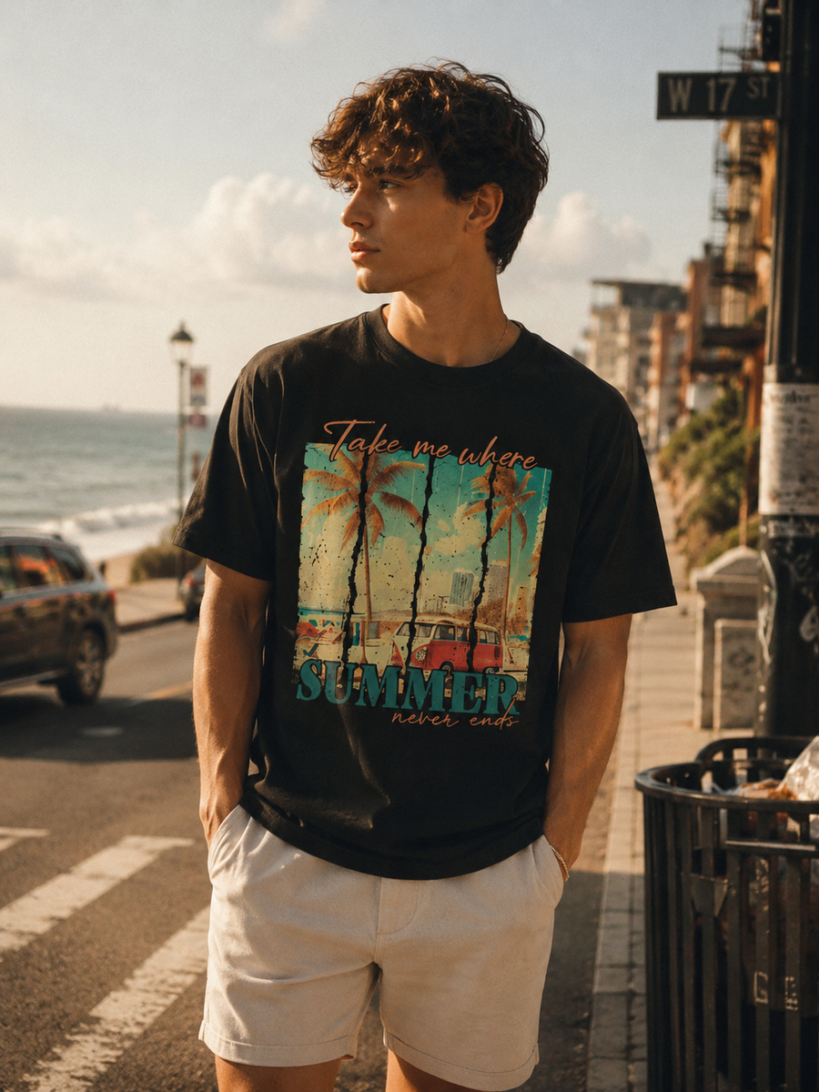 Man wearing a black t-shirt with a colorful graphic and text, standing on a street near the ocean.