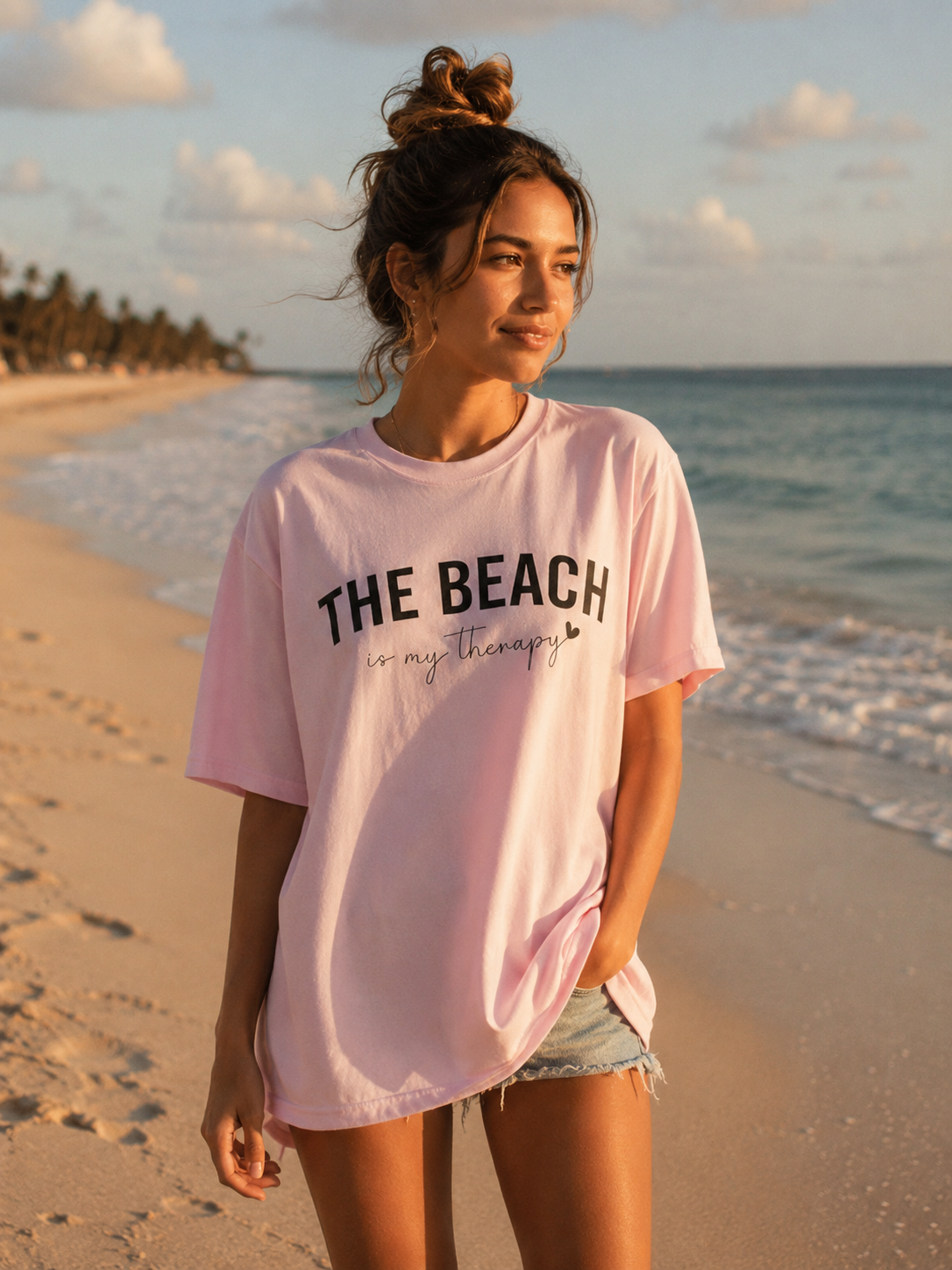 Woman wearing a pink t-shirt with 'The Beach is my therapy' on a beach