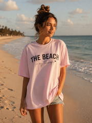 Woman wearing a pink t-shirt with 'The Beach is my therapy' on a beach
