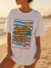 Woman wearing a 'Sunshine State of Mind' t-shirt on a beach at sunset