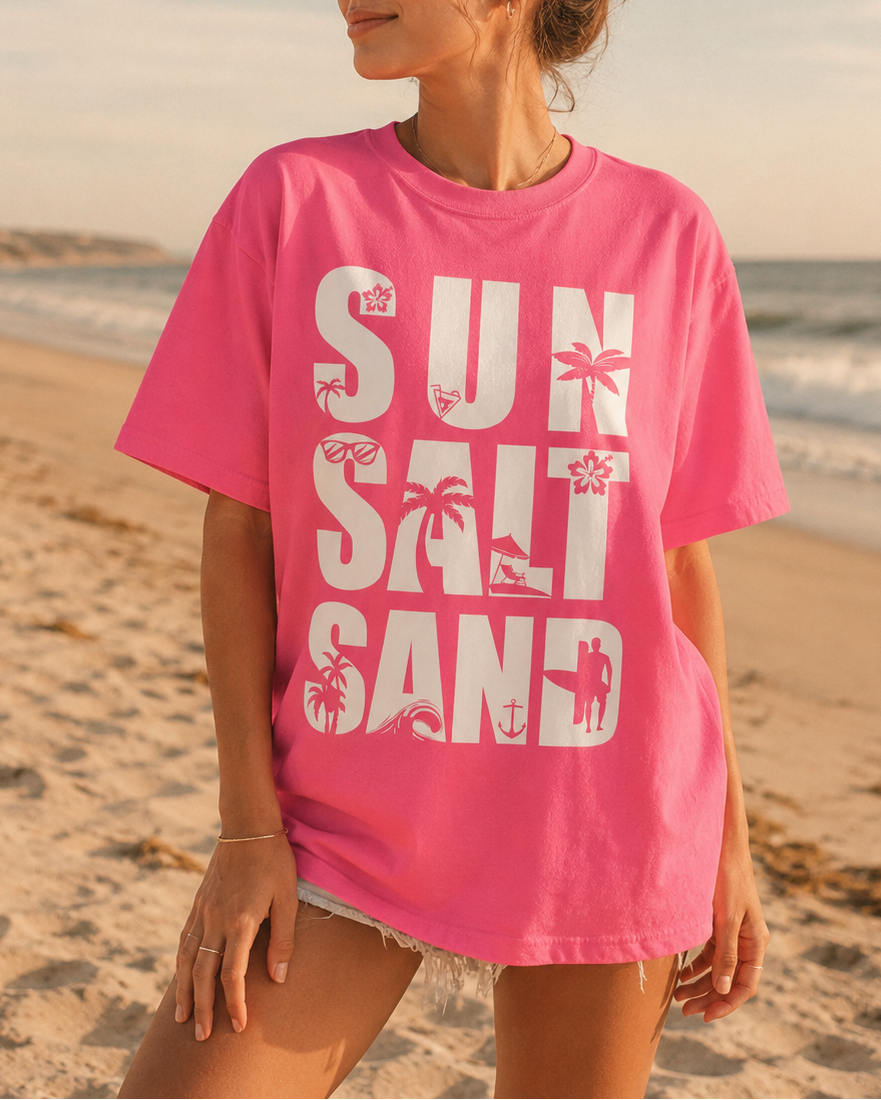 Woman wearing a pink t-shirt with 'Sun Salt Sand' text on a beach