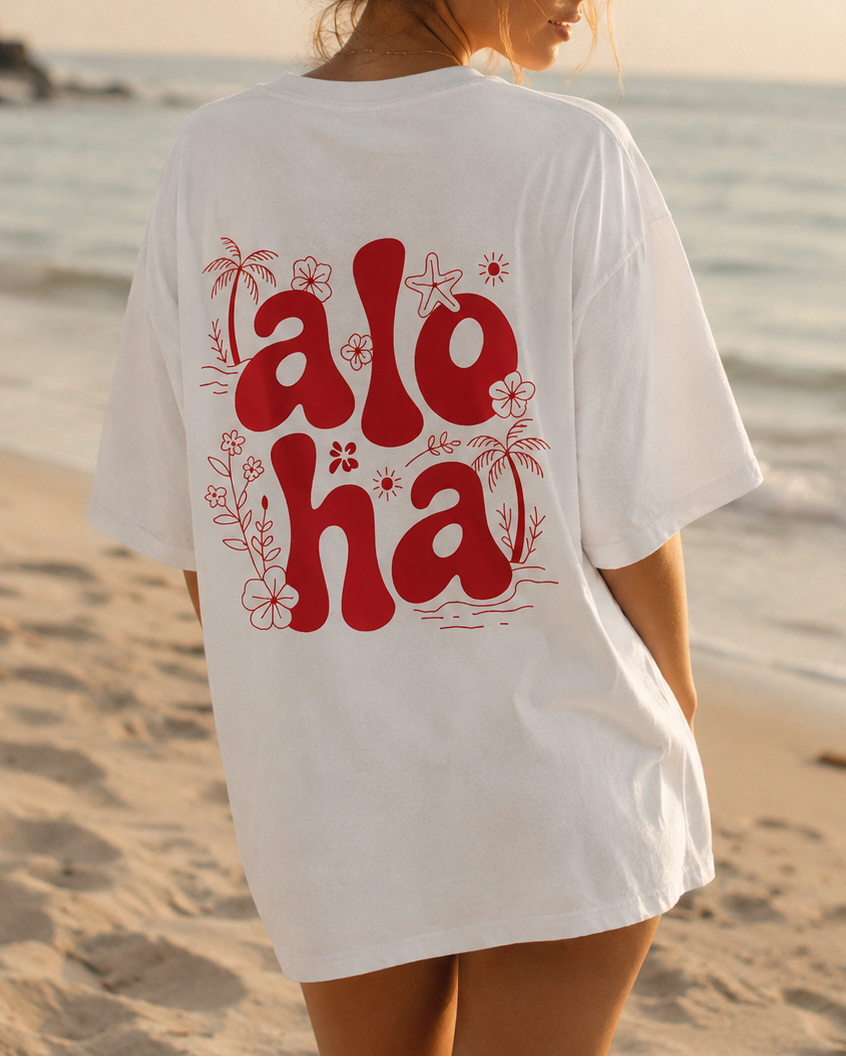 Woman wearing a white t-shirt with 'aloha' printed on the back at the beach. image 1