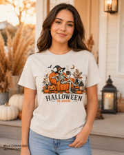 Female model wearing the Bella Canvas 3001 Heather Dust Halloween Is Good skeleton pumpkin chair T-shirt