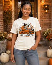 Female model wearing the Bella Canvas 3001 Natural Halloween Is Good skeleton pumpkin chair T-shirt