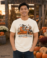 Male model wearing the Bella Canvas 3001 Natural Halloween Is Good skeleton pumpkin chair T-shirt