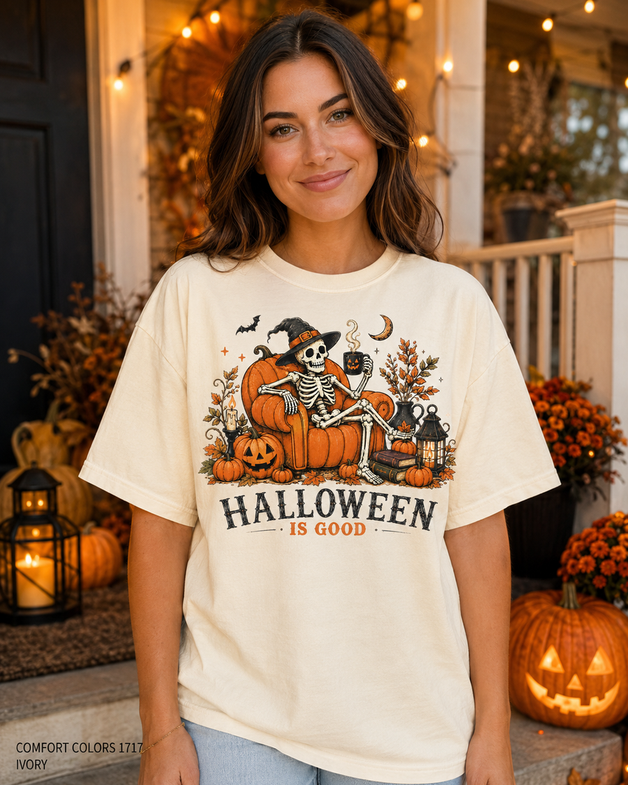 Female model wearing the Comfort Colors 1717 Ivory Halloween Is Good skeleton pumpkin chair T-shirt