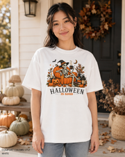 Female model wearing the Comfort Colors 1717 White Halloween Is Good skeleton pumpkin chair T-shirt