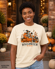 Female model wearing the Gildan 2000 Natural Halloween Is Good skeleton pumpkin chair T-shirt
