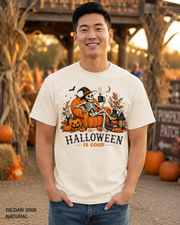 Male model wearing the Gildan 2000 Natural Halloween Is Good skeleton pumpkin chair T-shirt