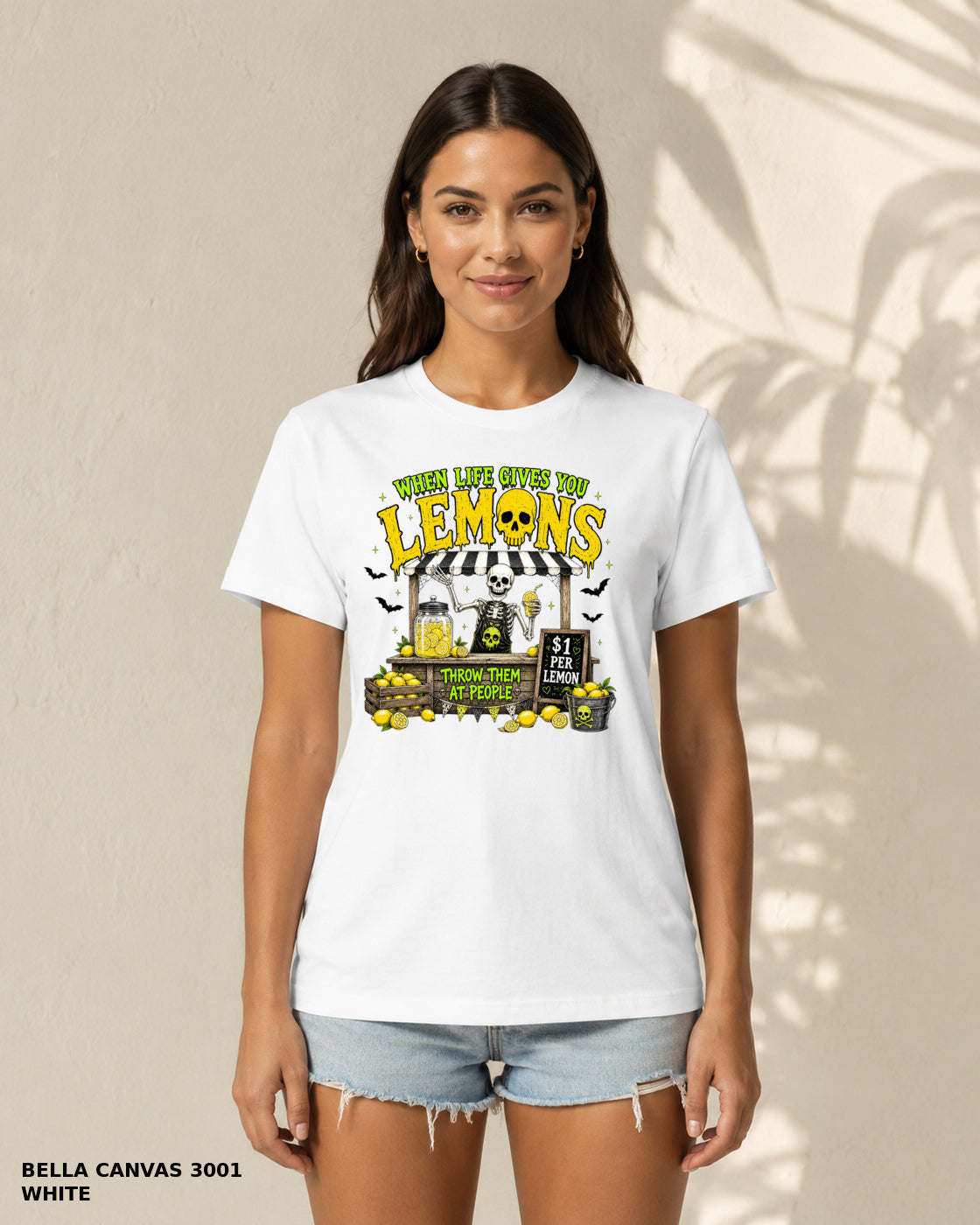 Female model wearing Bella Canvas 3001 White When Life Gives You Lemons skeleton Halloween T-shirt, artwork positioned slightly lower